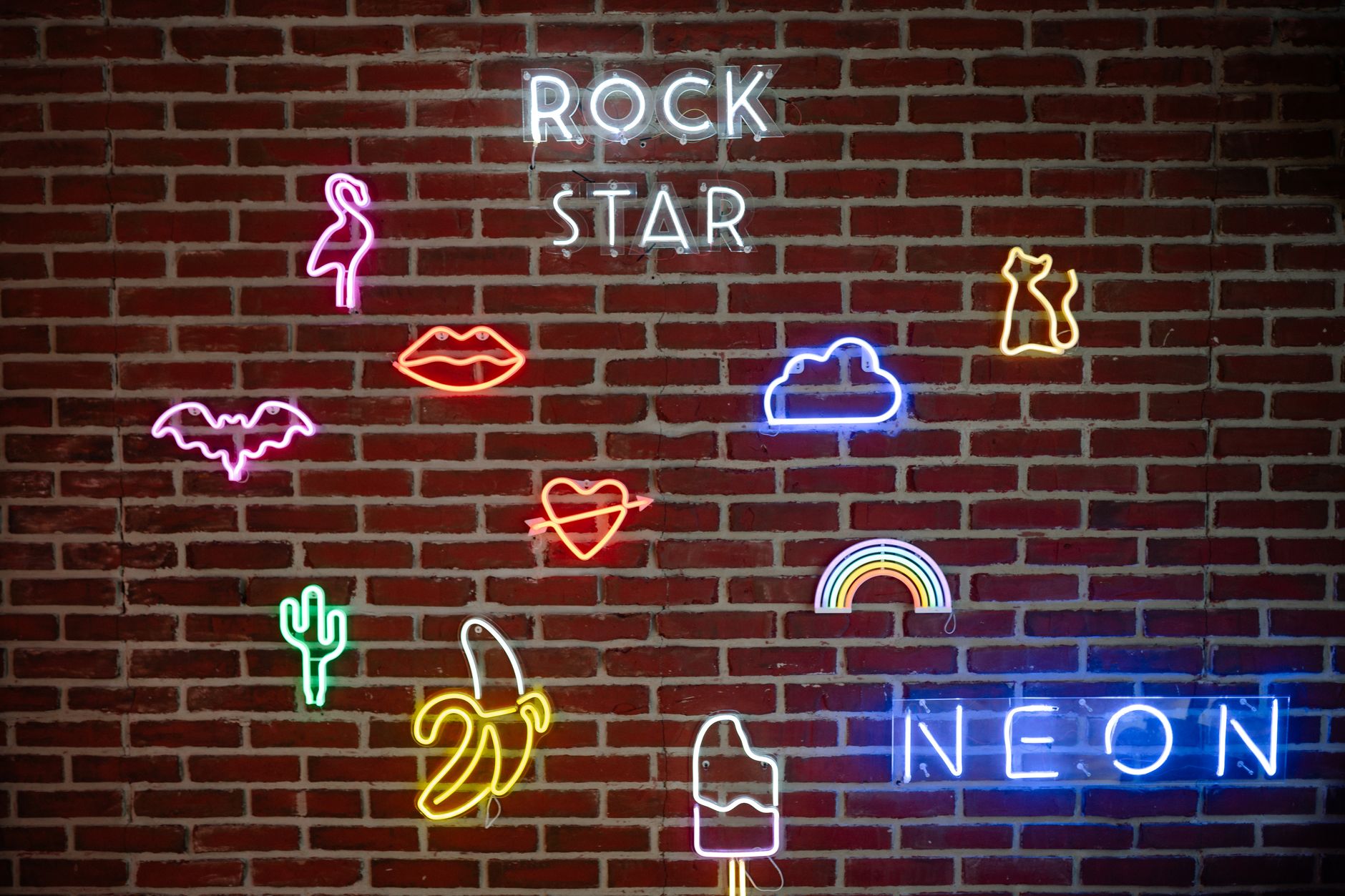 Colorful custom neon icon signs mounted on a brick wall